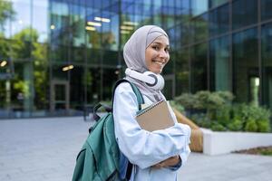 A contemporary student carrying a backpack and books walks in front of a glass building, exuding confidence and purpose. photo