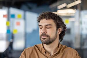 un sereno hombre con ojos cerrado practicando atención plena en un ocupado moderno oficina configuración, enfoque en estrés alivio y mental bienestar. foto