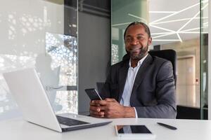 retrato de satisfecho tratado hombre dentro oficina, empresario sonriente y mirando a cámara, participación inhalador para respiración alivio y asma a lugar de trabajo. foto