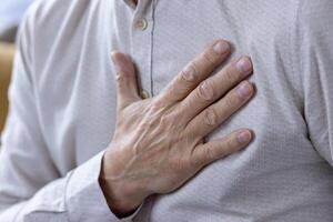 This image captures a close-up view of a middle-aged man feeling his heartbeat. The focus is on his hand and the texture of his shirt, conveying a sense of health and wellness. photo