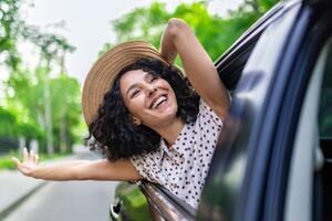 joven niña de viaje por auto, Hispano mujer con Rizado pelo mirando fuera el ventana, disfrutando vacaciones y viajar. foto