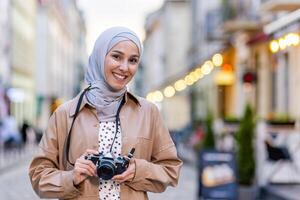 retrato de joven hermosa musulmán mujer en hiyab, turista caminando en noche ciudad con cámara, mujer de viaje a diferente países foto