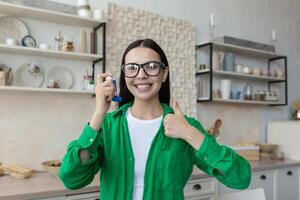 Girl showing an asthma inhaler sitting on a couch in the living room at home. photo