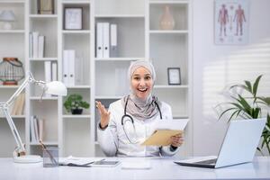 un profesional musulmán hembra médico vistiendo un hijab irradia positividad como ella consulta con pacientes en su brillante clínica oficina. foto