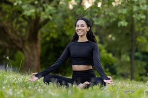 contenido joven hembra en ropa deportiva disfruta yoga meditación en pacífico parque, encarnando bienestar y consciencia. foto