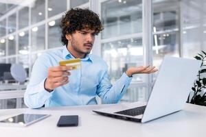 trastornado y engañado empresario dentro oficina molesto a transferir dinero en línea, nervioso hombre participación banco crédito tarjeta, tiene rechazado y error de fondos en cuenta negativo balance. foto