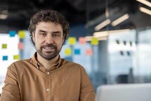 Portrait of a confident professional man with a warm smile, standing in a modern office with blurry background. photo