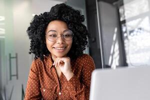 joven hembra empleado programador trabajando a lugar de trabajo dentro oficina con computadora portátil, negocio mujer mecanografía en teclado felizmente sonriente, satisfecho con trabajo y logro resultados. foto