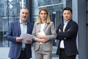 A team of experienced team leaders and specialists, a diverse group of business people, three people in business clothes are serious and focused in business clothes looking at the camera photo
