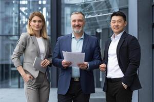 Successful mature business team man and woman businessmen in business suits smiling and looking at camera outside office building and specialist investors team smiling and happy photo