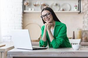 Portrait of a young beautiful woman in glasses and a green shirt, brunette at home photo