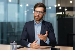 Webcam call view, happy mature boss talking to colleagues remotely, man looking at camera sitting in office, investor on online meeting with partners friendly smiling and chatting. photo