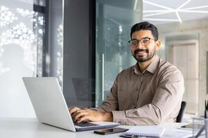 enfocado indio empresario utilizando ordenador portátil a el oficina. concepto de profesionalismo y moderno negocio ambiente. foto