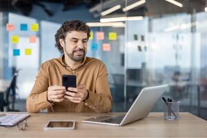 Professional hispanic man with a mature smile using a smartphone in a modern office environment, reflective of productivity and connectivity. photo