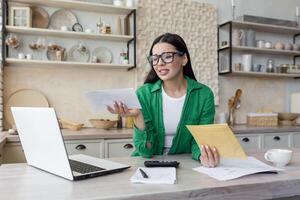 disappointed woman at home with paper work, brunette in kitchen counting bills. photo