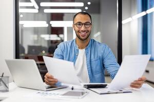 Professional Indian businessman analyzing documents in a contemporary office setting, focused and dedicated. photo