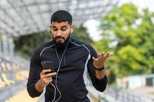 Frustrated athlete checking phone during workout at stadium photo