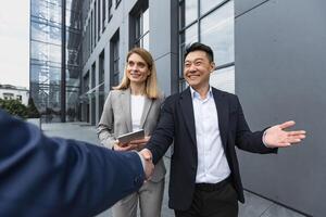 Men in business suits greet and shake hands, team of diverse business people meet outside office building photo