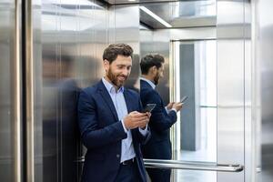 Confident businessman in a suit smiling at his phone in an elevator, reflecting success and connectivity. photo