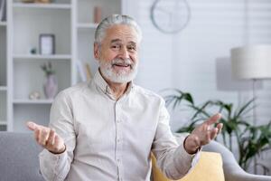 Elderly gentleman comfortably engaged in a call from his well-lit living room, portraying a casual and relaxed discussion. photo