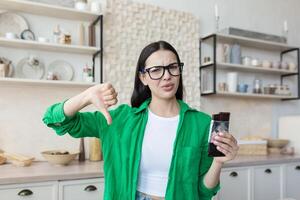 Woman at home disapproving of a bar of chocolate, looking at the camera and pointing a finger down photo