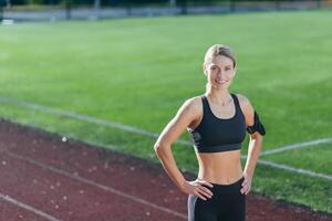 Portrait of sportswoman in sportswear at stadium, blonde smiling and looking at camera, woman before morning workout and exercise and fitness. photo