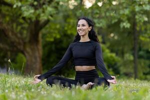 Young woman immersed in meditation, performing yoga in a peaceful green park, embodying health and mindfulness. photo