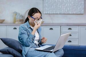 Online consultation with a psychologist, an Asian woman in glasses is alone at home photo