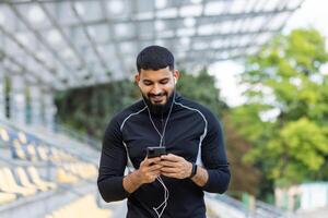 joven hombre disfrutando música en teléfono inteligente a estadio foto