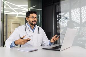 un médico es hablando a un paciente en un ordenador portátil foto