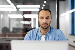 enfocado profesional quedarse tarde a el oficina, trabajando diligentemente en un proyecto en un contemporáneo espacio de trabajo foto