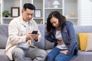 familia Pareja hombre y mujer sentado en sofá a hogar asiático familia hombre molesto a llamada médico para enfermo esposa. foto