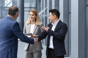 Three experienced managers team leaders, meet and get to know from outside the office team, diverse group of entrepreneurs shake hands men, introduce new colleague photo