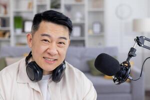 Cheerful male podcaster with headphones speaks into a microphone, recording content in a cozy home studio setting. photo