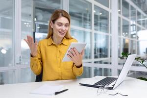Woman at workplace using tablet computer, got winning achievement results, business woman celebrating victory success and triumph, inside office at workplace. photo
