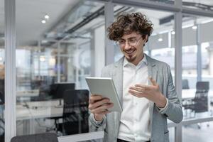 comprometido joven adulto en un ocupado oficina configuración, saliente competencia y positividad mientras utilizando un digital tableta. transporta un puede hacer actitud. foto