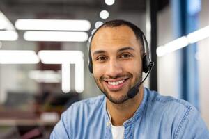 un enfocado masculino profesional trabajos eficientemente con un auriculares en un brillantemente iluminado moderno oficina ajuste. foto