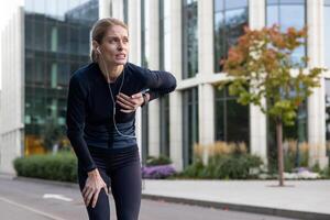 fatigado mujer atleta pausar para descanso en medio de un correr en un ciudad configuración, vistiendo ropa de deporte, sensación cansado. foto