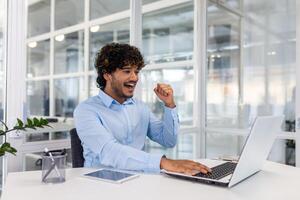 Confident professional working at a tidy desk with laptop in a bright, contemporary office setting. photo