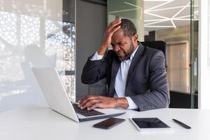 insatisfecho y trastornado africano americano hombre a lugar de trabajo, maduro experimentado jefe decepcionado con financiero resultados de logro dentro oficina, arruinado banquero inversor. foto