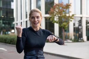 energético hembra corredor celebrando victoria al aire libre con un puño bomba, exhibiendo alegría, logro, y bienestar. foto