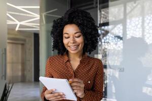 A smiling young professional woman in a stylish polka dot shirt taking notes while engaging in a meeting in a modern office setting, exuding a friendly demeanor. photo