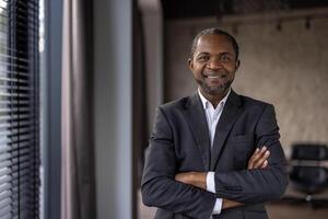 Portrait of a confident African American businessman with a warm smile standing in a modern office setting. photo