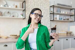 Young satisfied woman at home eating chocolate bar in kitchen photo