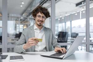 confidente masculino oficina trabajador se involucra en en línea actas, demostración trabajo competencia y positivo emociones a su lleno de luz lugar de trabajo. foto