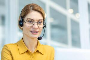 Closeup of successful businesswoman working remotely from home, worker of online logistics center of transportation smiling and consulting customers, woman in shirt working office sitting by window. photo