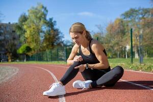 Active woman in sportswear feeling severe pain in her leg, pausing her track workout to deal with a sudden injury. photo