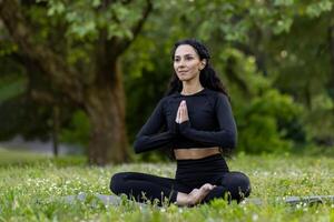 un joven mujer es capturado en un momento de tranquilidad mientras practicando yoga en el sereno ajuste de un lozano parque. foto