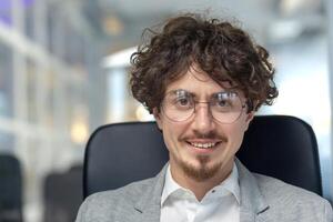 Professional young male with curly hair showcasing confidence and expertise in a corporate office environment. photo