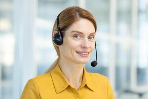 Portrait of mature female customer service worker, mature business woman with call headset smiling and looking at camera, call center online customer service, inside office at workplace. photo